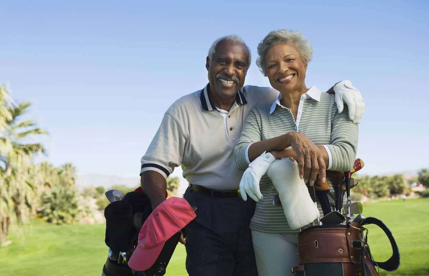 A senior living couple smiling while golfing